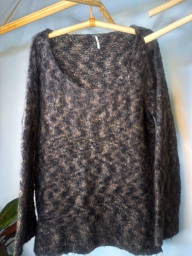 May include: A brown and black fuzzy knit sweater with a scoop neck and long sleeves.