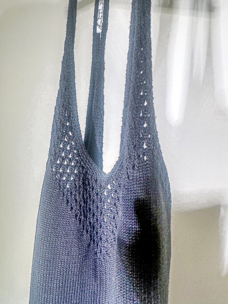 Puede incluir: Un top de tirantes de crochet azul oscuro con un delicado patr&oacute;n de calado. El top tiene un escote en V y tirantes finos.