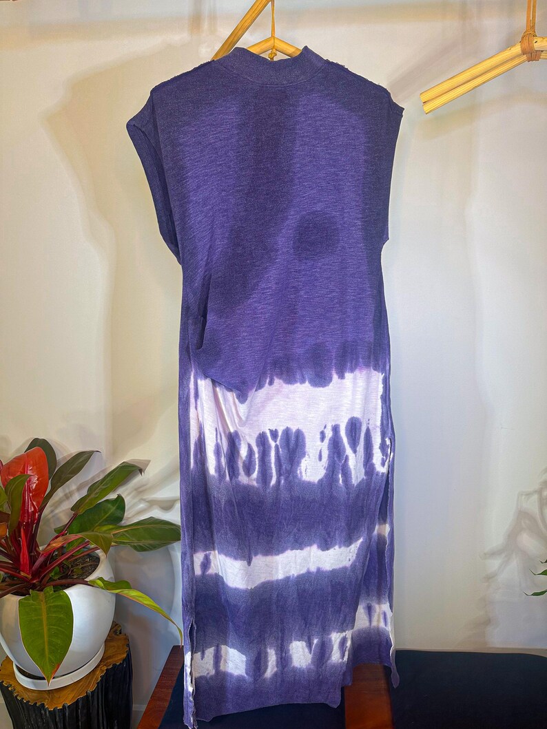 May include: A purple and white tie-dye sleeveless dress with a high neck and a side slit. The dress is made of a soft, lightweight fabric.