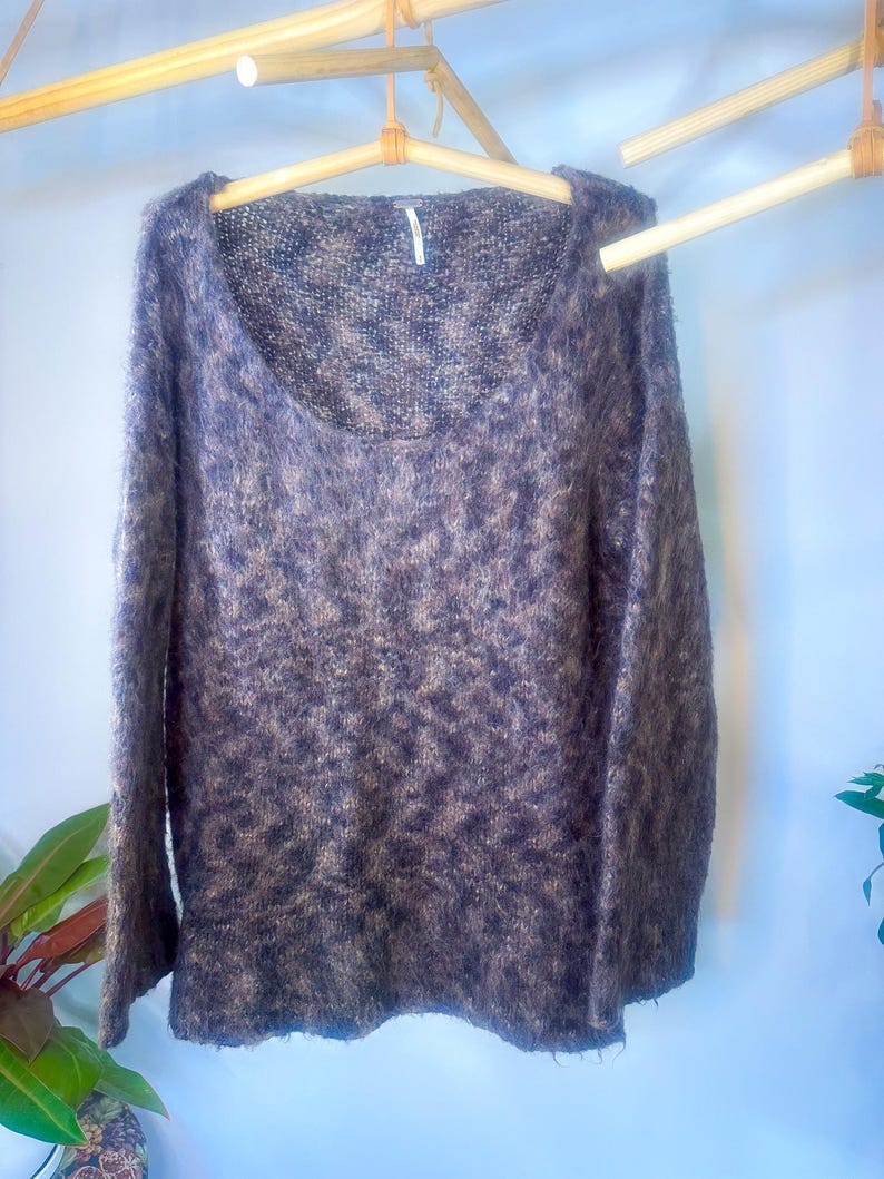 May include: A brown and beige fuzzy knit sweater with a scoop neck and long sleeves.