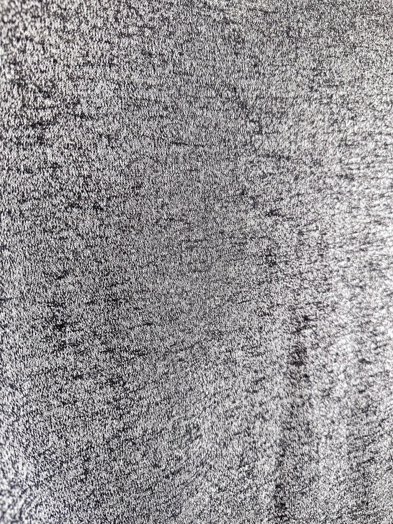 May include: Close-up of a textured, black fabric with a subtle sheen. The fabric has a fine, woven pattern.