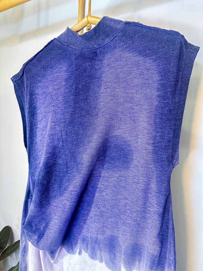 May include: A sleeveless, blue and white ombre, tie-dye shirt with a mock neck.