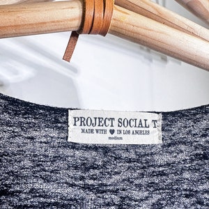 May include: A gray and white striped t-shirt with a white tag that reads "PROJECT SOCIAL T. MADE WITH &hearts; IN LOS ANGELES medium".