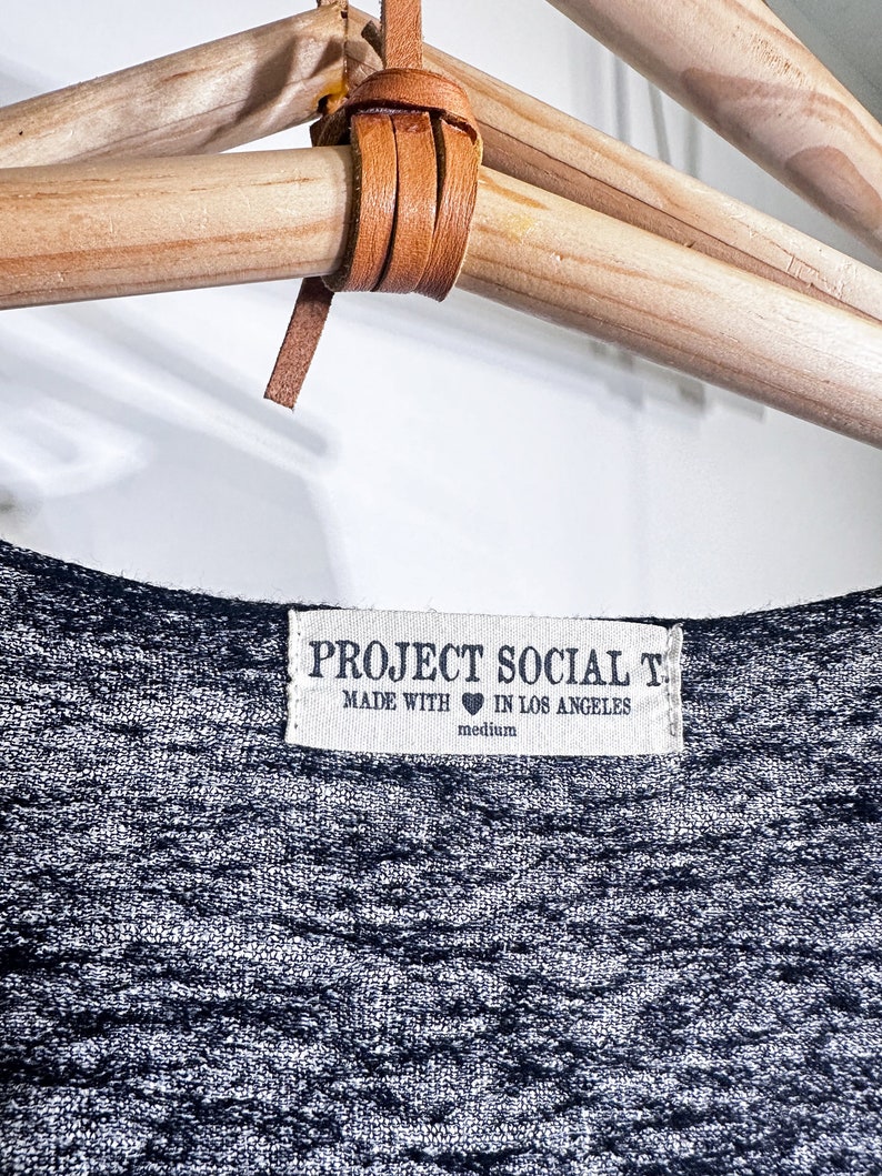 May include: A gray and white striped t-shirt with a white tag that reads "PROJECT SOCIAL T. MADE WITH &hearts; IN LOS ANGELES medium".