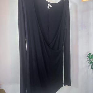 Puede incluir: Camiseta negra de manga larga con cuello en V profundo y dise&ntilde;o de envoltura. La camiseta est&aacute; hecha de una tela suave y el&aacute;stica.