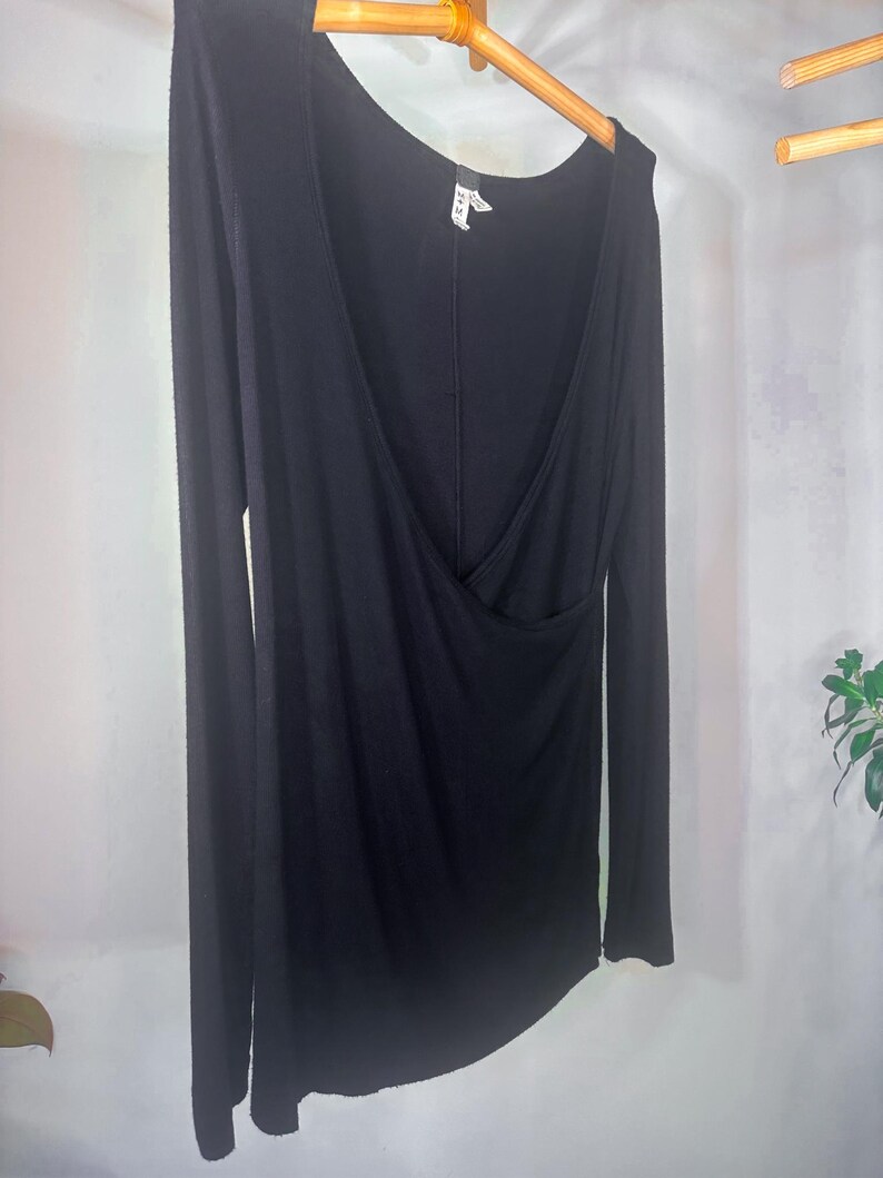 Puede incluir: Camiseta negra de manga larga con cuello en V profundo y dise&ntilde;o de envoltura. La camiseta est&aacute; hecha de una tela suave y el&aacute;stica.