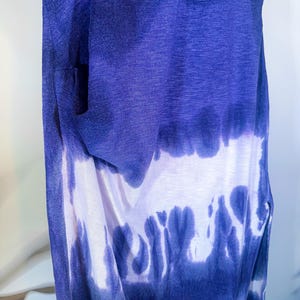 May include: A sleeveless tie-dye dress with a blue and white ombre pattern. The dress is made of a soft, lightweight fabric and has a relaxed fit.