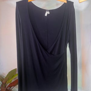 Puede incluir: Una camisa negra de manga larga con un escote de estilo envolvente. La camisa est&aacute; hecha de una tela suave y el&aacute;stica y tiene un ajuste holgado.