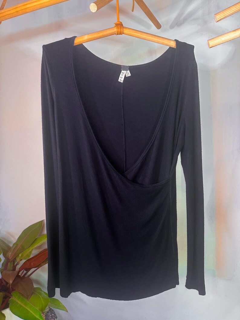 Puede incluir: Una camisa negra de manga larga con un escote de estilo envolvente. La camisa est&aacute; hecha de una tela suave y el&aacute;stica y tiene un ajuste holgado.