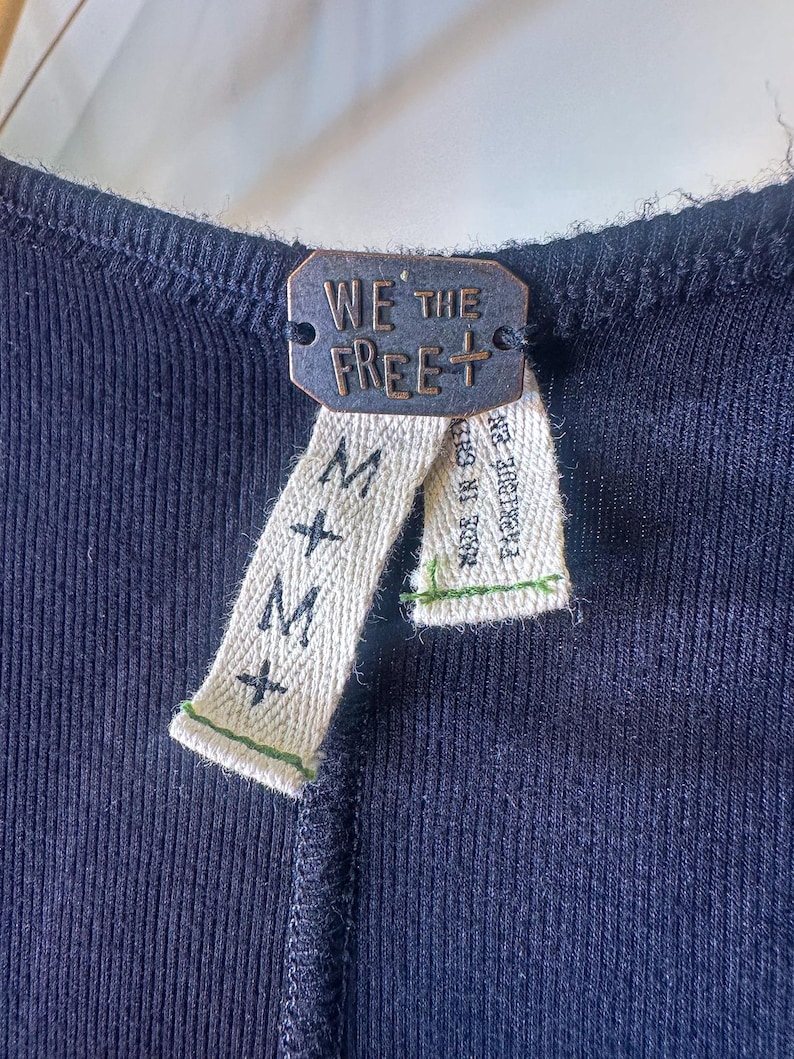Puede incluir: Un top de tanque negro de canal&eacute; con una etiqueta We The Free+ y una etiqueta de talla M.