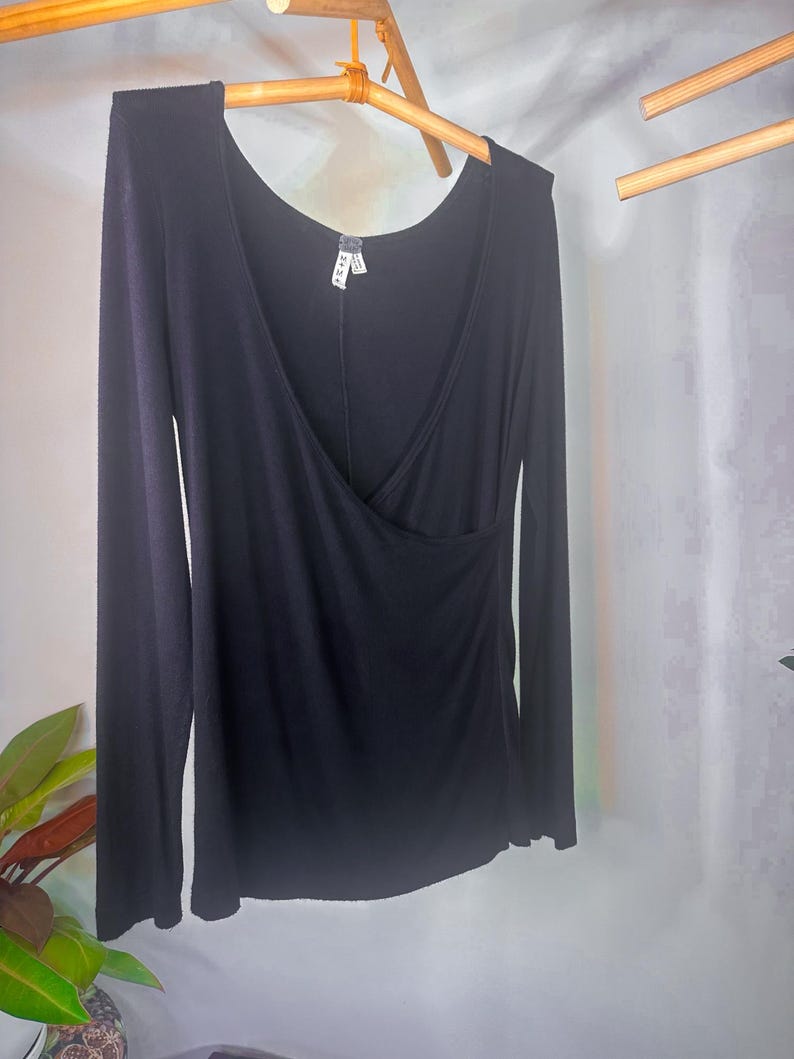 Puede incluir: Camiseta negra de manga larga con escote cruzado. La camiseta est&aacute; hecha de un tejido suave y el&aacute;stico.