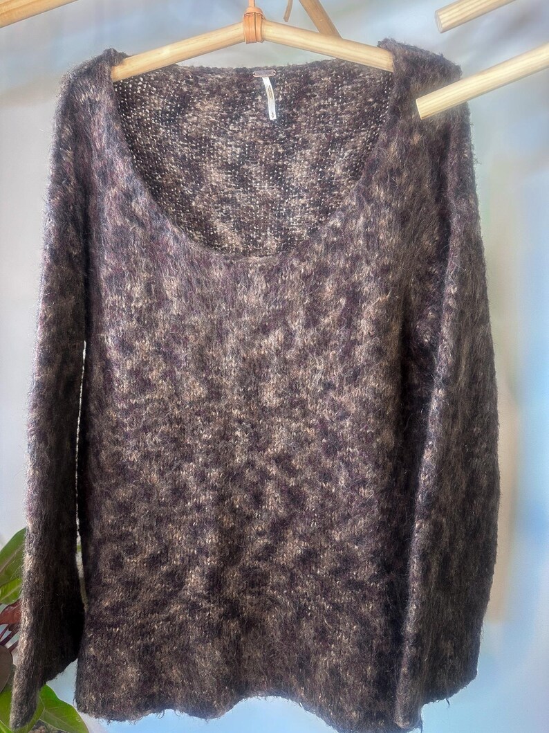 May include: A brown and beige fuzzy knit sweater with a scoop neck and long sleeves.
