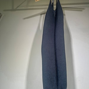 Puede incluir: Un vestido negro de punto sin mangas colgado de una percha de madera.