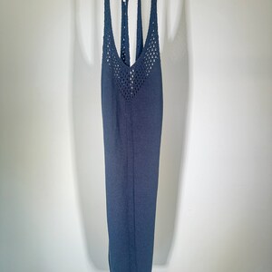 Puede incluir: Un top de punto azul oscuro sin mangas con un patr&oacute;n de crochet en la parte delantera y un escote en V.