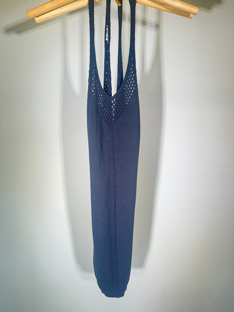 Puede incluir: Un top de punto azul oscuro sin mangas con un patr&oacute;n de crochet en la parte delantera y un escote en V.