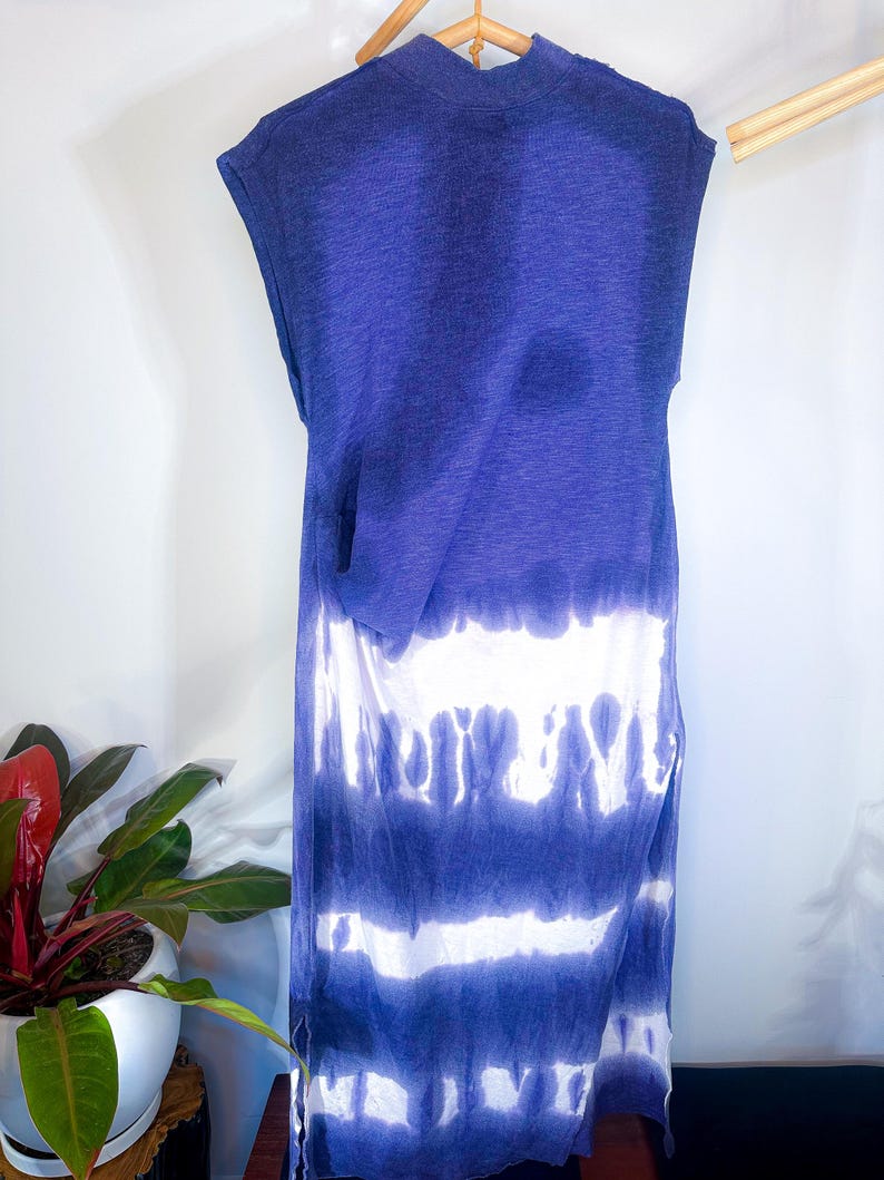 May include: A long, sleeveless, tie-dye dress in shades of blue and white. The dress has a relaxed fit and a slightly gathered waist.