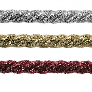 Op de afbeelding: Drie spoelen met gedraaide, glinsterende koord. De koorden zijn zilver, goud en rood.