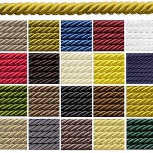 Op de afbeelding: Een selectie van decoratief gedraaid touw in verschillende kleuren, waaronder goud, beige, blauw, rood en wit. De afbeelding toont een close-up van een gouden touw bovenaan, met daaronder een raster van verschillend gekleurde touwmonsters.