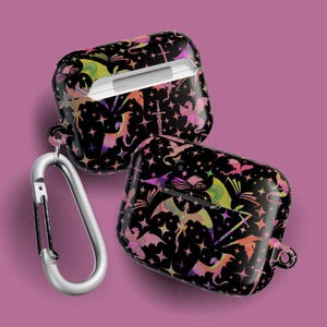 May include: Two black AirPod cases with a fantasy design of dragons, stars, books, and swords in pink, purple, yellow, and orange. A silver carabiner clip is attached to one case. The cases are on a pink background.
