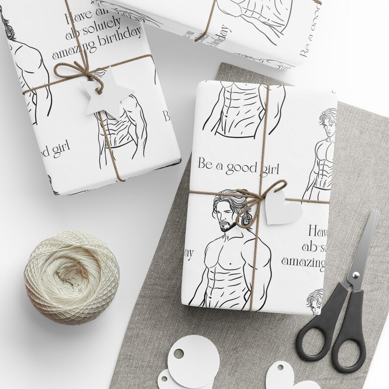 May include: White gift wrap featuring a black line drawing of a muscular man. The paper is tied with twine and a star-shaped tag. Text on the wrap includes "Be a good girl" and "Have an absolutely amazing birthday."