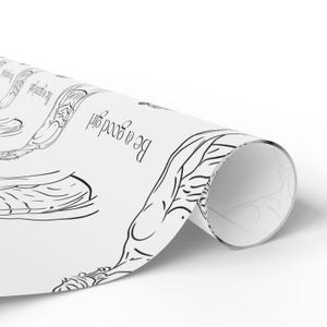 May include: White wrapping paper featuring a black line drawing of a figure and the words "Be a good girl". The paper is rolled, revealing both the printed side and the plain white interior.