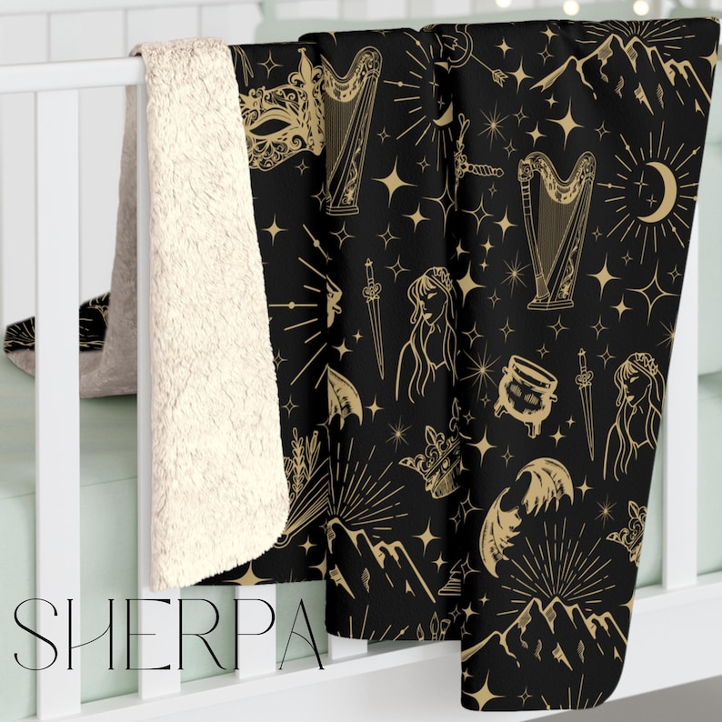 Fantasy inspired blanket with a celestial print in tan on a black blanket, the pattern includes images of moons, masks, bat wings, books, harp, fae and stars for fans of acotar and sarah j maas