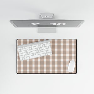 May include: A brown and white checkered desk mat with a white keyboard and mouse on top. The desk mat has a black border.