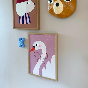 May include: A framed print of a white swan with a red bow on a pink background with white polka dots.