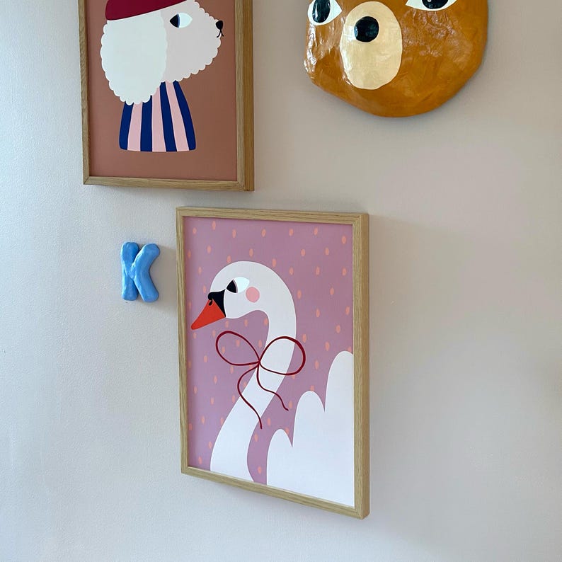 May include: A framed print of a white swan with a red bow on a pink background with white polka dots.