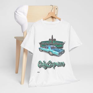 May include: White t-shirt with a teal blue car graphic and the text "The Box Chevy Movement" and "Only Caprices" in a green neon font.