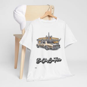 May include: White t-shirt with a brown and gold illustration of a classic car. The text "The Box Chevy Movement" and "Box Chevy Since The 80s" is printed on the shirt.