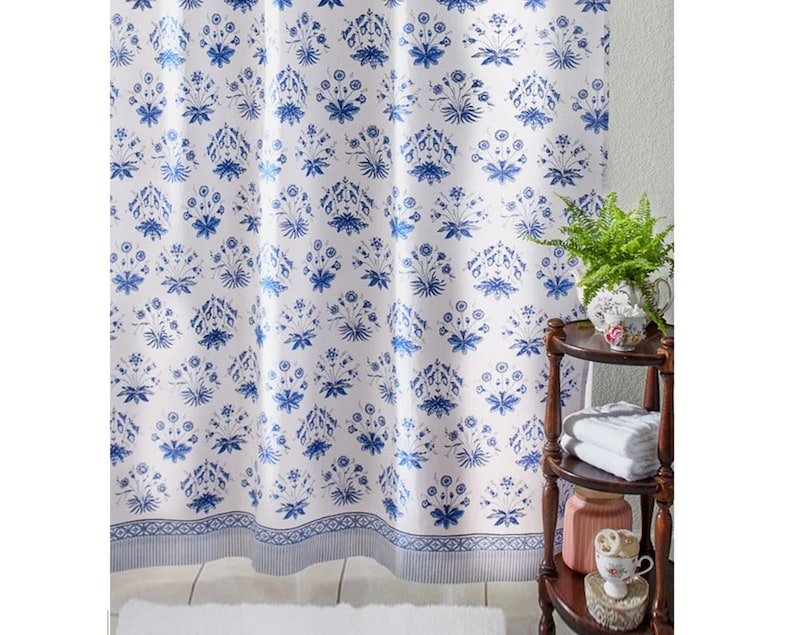 May include: White shower curtain with a blue floral pattern. The pattern features small blue flowers and leaves on a white background. The curtain has a blue and white border.