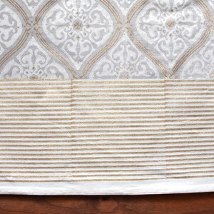 May include: White fabric with a gray and white geometric pattern and a gold stripe border.