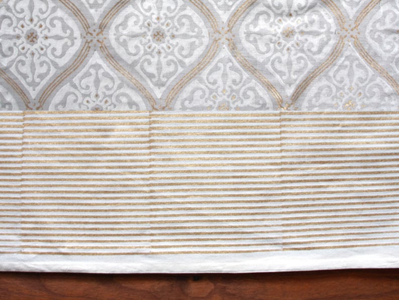 May include: White fabric with a gray and white geometric pattern and a gold stripe border.