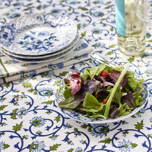 K&ouml;nnte beinhalten: Eine wei&szlig;e Tischdecke mit einem blauen und gr&uuml;nen Blumenmuster. Ein wei&szlig;er Teller mit einem blauen und gr&uuml;nen Blumenmuster steht auf dem Tisch. Ein Salat mit gr&uuml;nem Salat, roten Tomaten und gr&uuml;nen Zwiebeln liegt auf dem Teller.
