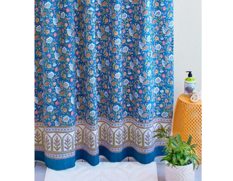 May include: A blue shower curtain with a floral pattern. The curtain has a white border with a repeating design of arches and flowers.