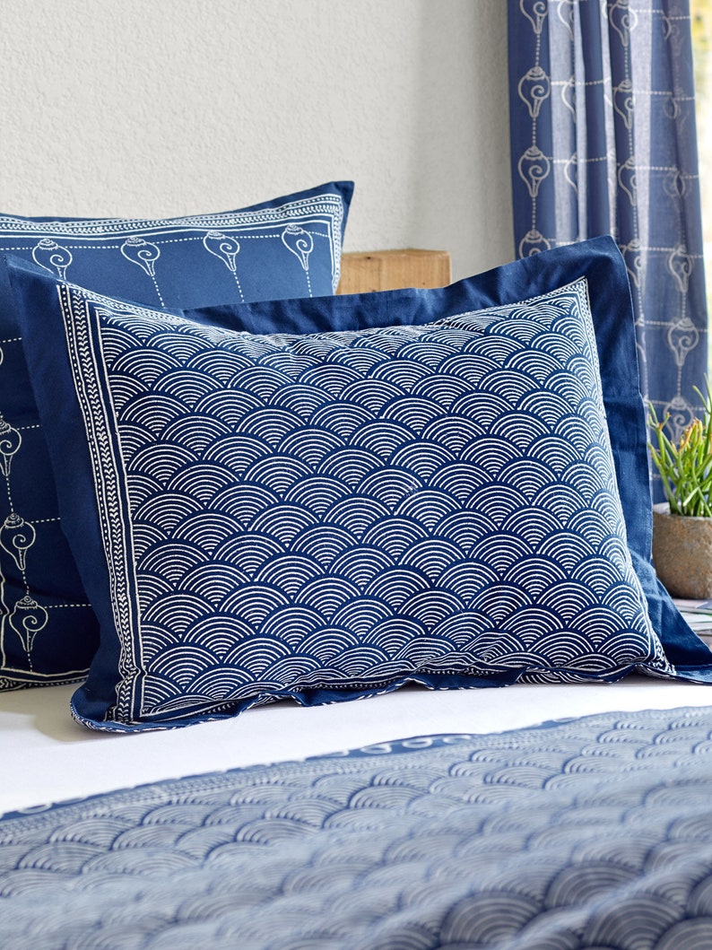 May include: Two blue pillowcases with white geometric patterns. The pillowcase on top has a pattern of overlapping half circles. The pillowcase on the bottom has a pattern of small, repeating symbols.