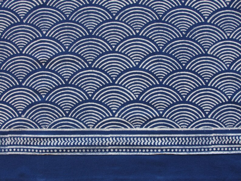 May include: Indigo blue fabric with a white geometric pattern of overlapping semi-circles. The fabric has a white border with a repeating pattern of small white dots and leaves.