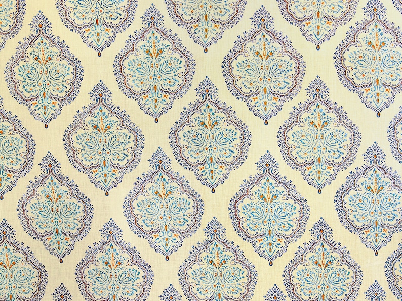 Puede incluir: Tela de color crema con un patr&oacute;n repetido de dise&ntilde;os ornamentados en forma de l&aacute;grima. Cada dise&ntilde;o presenta un motivo floral central en tonos azules y naranjas, delineado con un borde azul oscuro. El efecto general es un patr&oacute;n detallado y sim&eacute;trico.