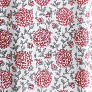 K&ouml;nnte beinhalten: Ein wei&szlig;er Stoff mit einem sich wiederholenden Muster aus rosa Bl&uuml;ten und grauen Bl&auml;ttern. Die Bl&uuml;ten sind stilisiert und haben einen leicht dreidimensionalen Effekt.
