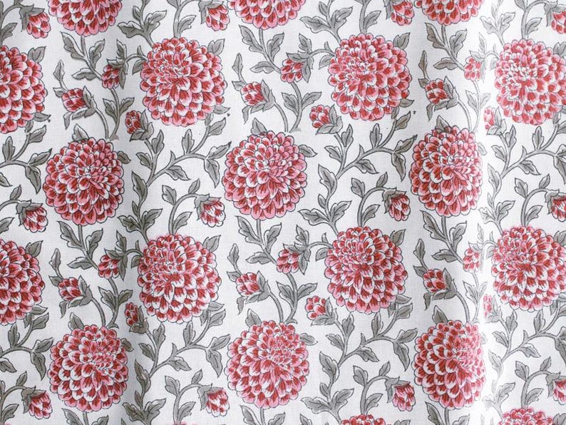 K&ouml;nnte beinhalten: Ein wei&szlig;er Stoff mit einem sich wiederholenden Muster aus rosa Bl&uuml;ten und grauen Bl&auml;ttern. Die Bl&uuml;ten sind stilisiert und haben einen leicht dreidimensionalen Effekt.