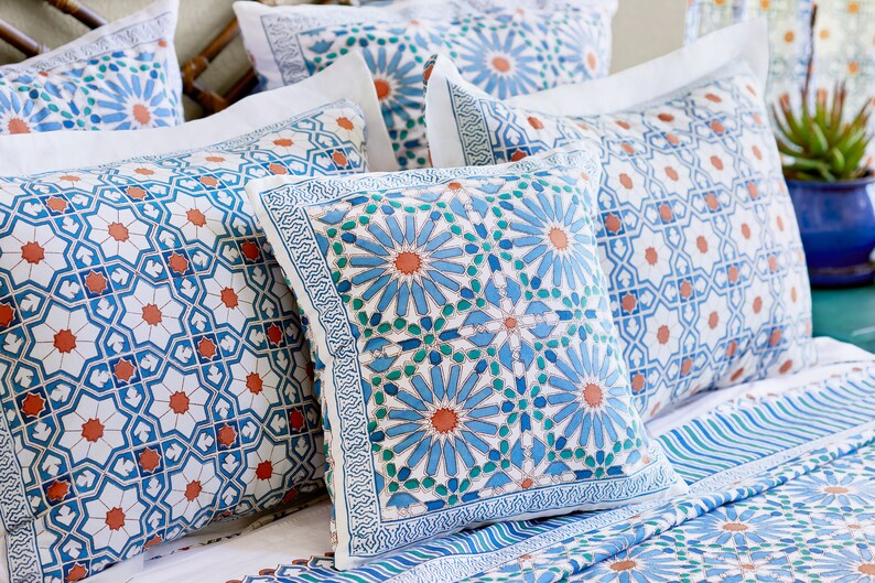 May include: A set of decorative throw pillows with a blue and white geometric pattern. The pillows feature a repeating design of stylized flowers and intricate details.
