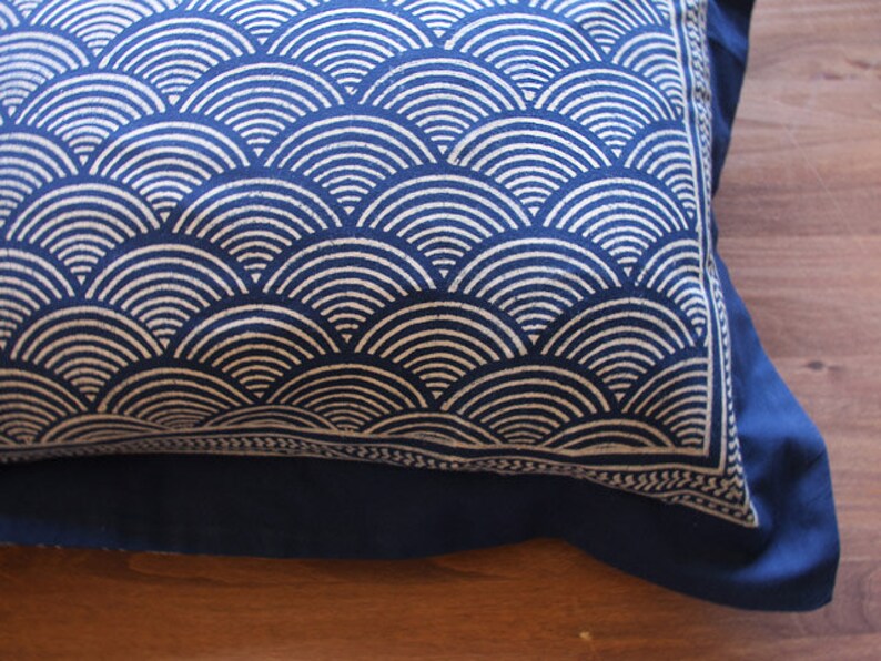 May include: A blue pillow with a white geometric pattern of overlapping semicircles. The pillow has a blue border and a blue backing.