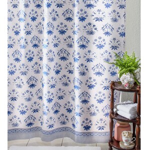 May include: White shower curtain with a blue floral pattern. The curtain has a blue border with a white stripe.