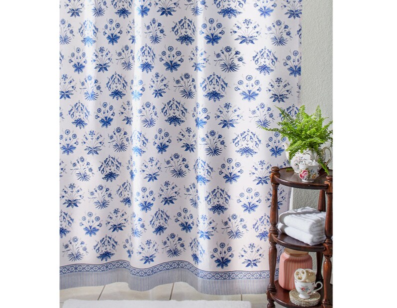 May include: White shower curtain with a blue floral pattern. The curtain has a blue border with a white stripe.