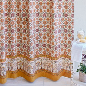 May include: A white shower curtain with a floral pattern in shades of orange, purple, and green. The curtain has a gold border and is hanging in a bathroom.