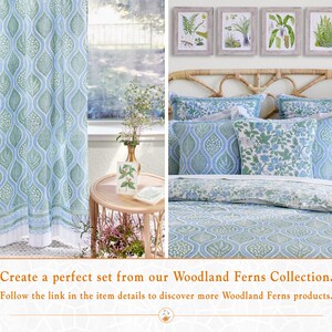 Op de afbeelding: Een beddengoedset met een blauw en groen patroon met een bloemenontwerp. Het beddengoed wordt getoond op een bed met een geweven hoofdeinde en een raam erachter. De tekst "Create a perfect set from our Woodland Ferns Collection. Follow the link in the item details to discover more Woodland Ferns products." wordt onderaan de afbeelding weergegeven.