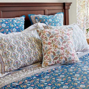 May include: A bed with a blue and white floral patterned duvet cover and matching pillowcases. There are three decorative pillows with floral patterns in shades of blue, white, and pink.