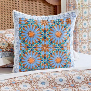 May include: A blue and orange patterned throw pillow with a geometric design. The pillow is on a bed with a matching patterned bedspread.