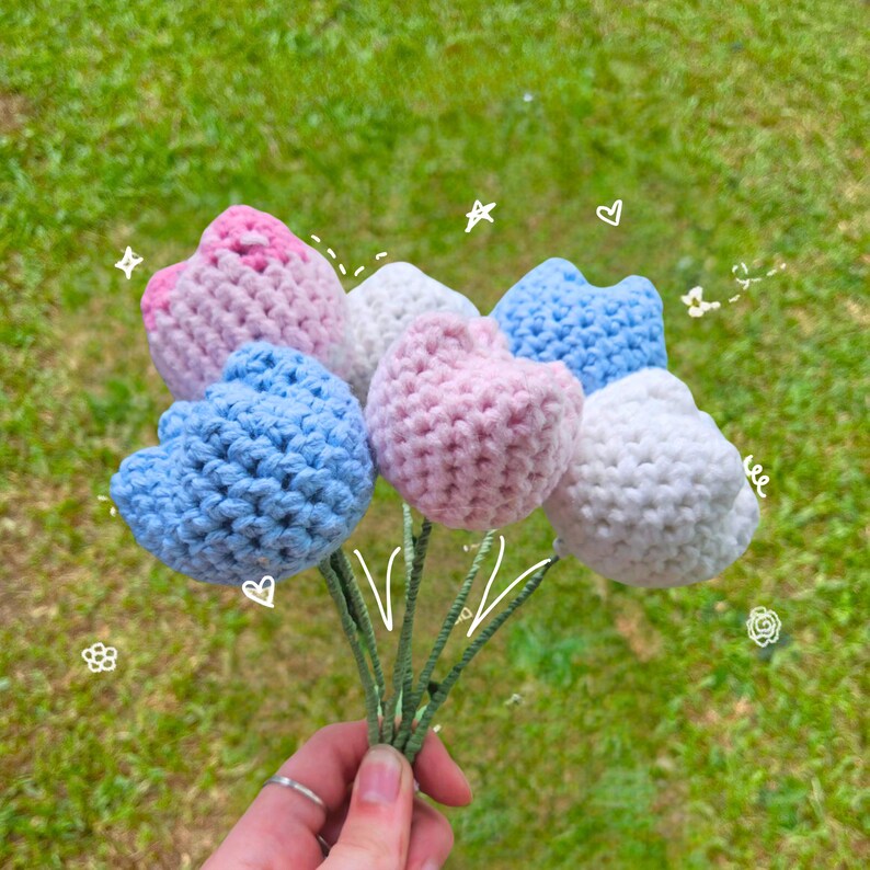 May include: A bouquet of crocheted flowers in pink, blue, and white. The flowers are shaped like tulips and are arranged in a bunch.